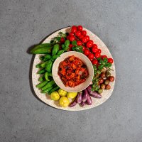 Caponata con decorazione di peperoni gialli e verdi, pomodorini e melanzane